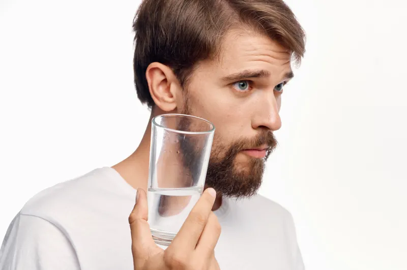 Бородатый мужчина со стаканом воды в студии