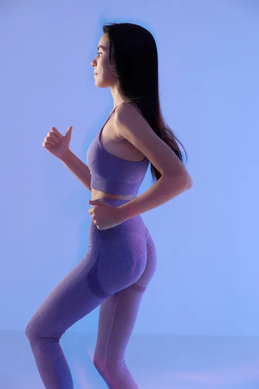 woman sport fitness jogging in seamless purple activewear, focused young Asian female exercising indoors with soft blue lighting, healthy lifestyle concept