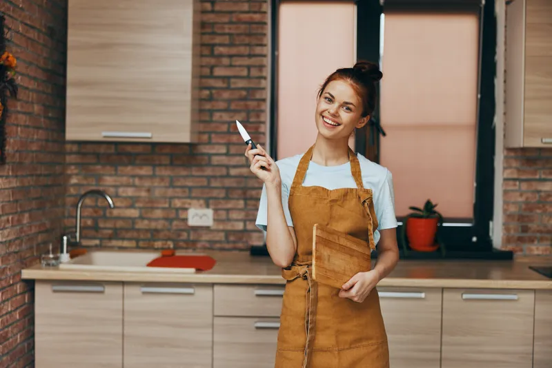 Домохозяйка на кухне с разделочной доской и ножом