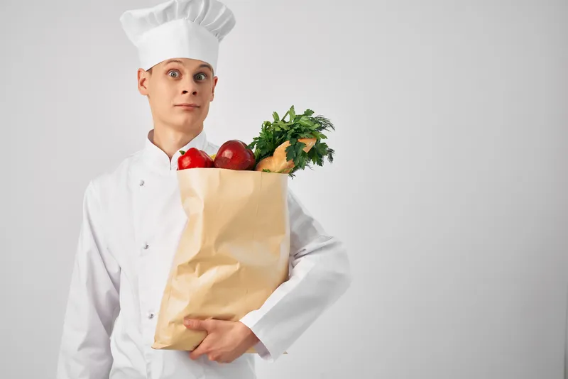 Шеф-повар с упаковкой свежих продуктов занимается доставкой из ресторана
