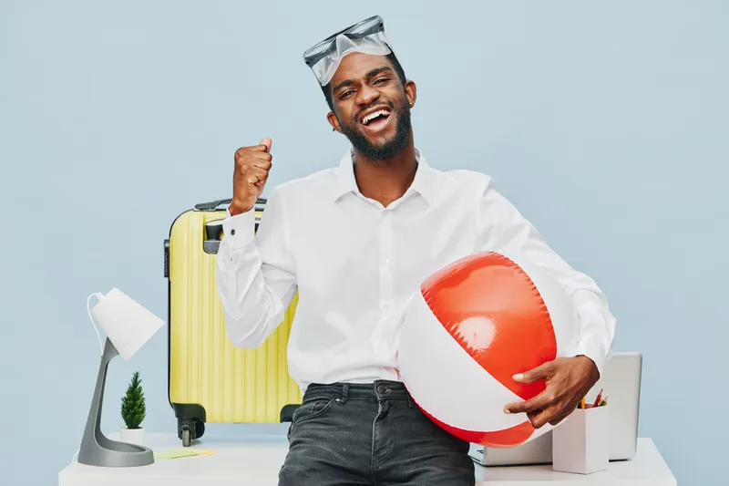 Cheerful young man with dark hair, beard, wearing white shirt and sunglasses, holding a red and white beach ball, promoting summer vacation and fun activities, indoor studio shot with light blue backg