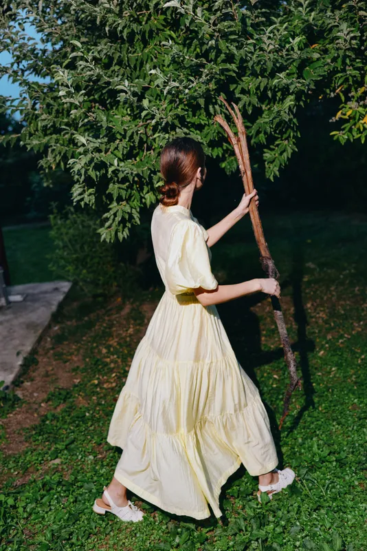 woman dress walking branch nature backyard summer evening authenticity inclusivity serene portrait of a female in flowing yellow dress