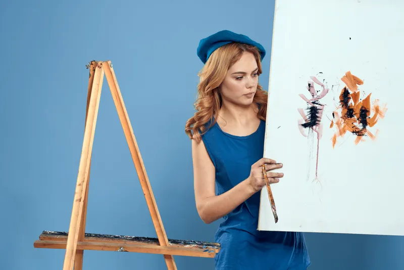 Женщина-художница держит в руке кисть, рисует, искусство, творческий образ жизни, синий фон