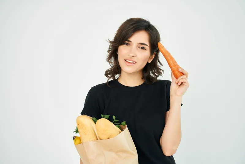 Женщина в чёрной футболке с пакетом продуктов, доставка здоровой еды, светлый фон