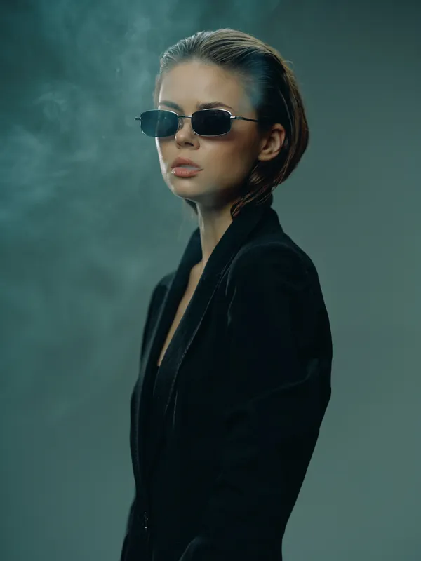 Stylish woman wearing sunglasses and black jacket with smoky background in cool modern fashion look.