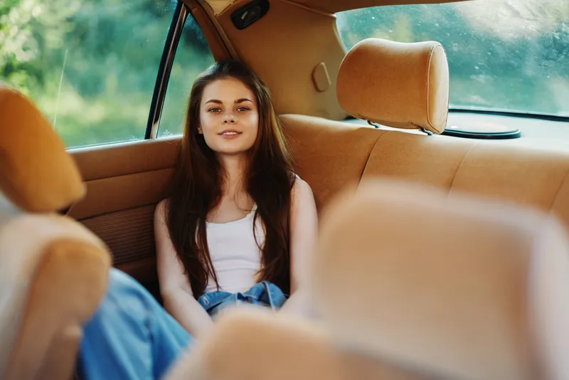 Young woman relaxing in car interior with natural light, showcasing laid-back style and summer vibe, emphasizing comfort and serenity.