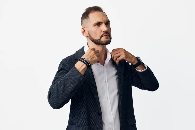 A professional business man adjusting his jacket against an isolated colored background, projecting confidence and focus. The moment signals leadership, purpose, and readiness to tackle tasks with