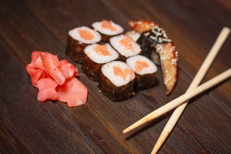 Азиатская кухня: роллы суши, деревянные палочки, васаби, имбирь, морепродукты