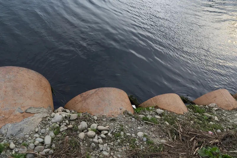 River rocks water shoreline outdoors nature pebbles landscape, calm flowing water over wet stones, tranquil lifestyle mood, soft natural light along the bank