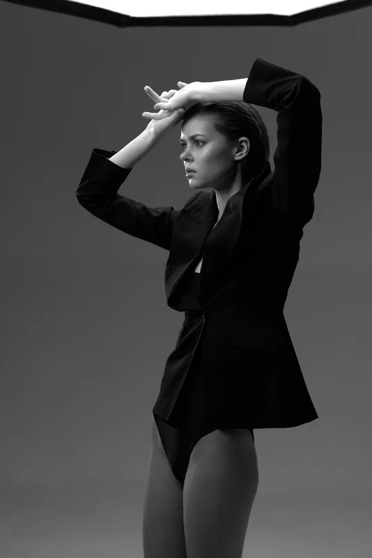 Black and white portrait of a young woman in a blazer posing thoughtfully with elegant style and strong expression