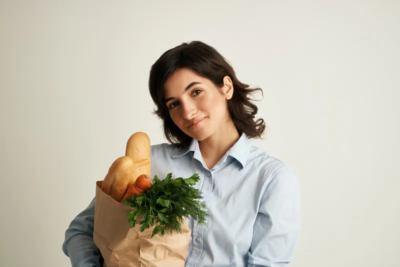Брюнетка доставляет продуктовый пакет из супермаркета