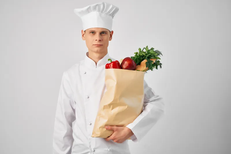 Шеф-повар с упаковкой свежих продуктов для доставки из ресторана
