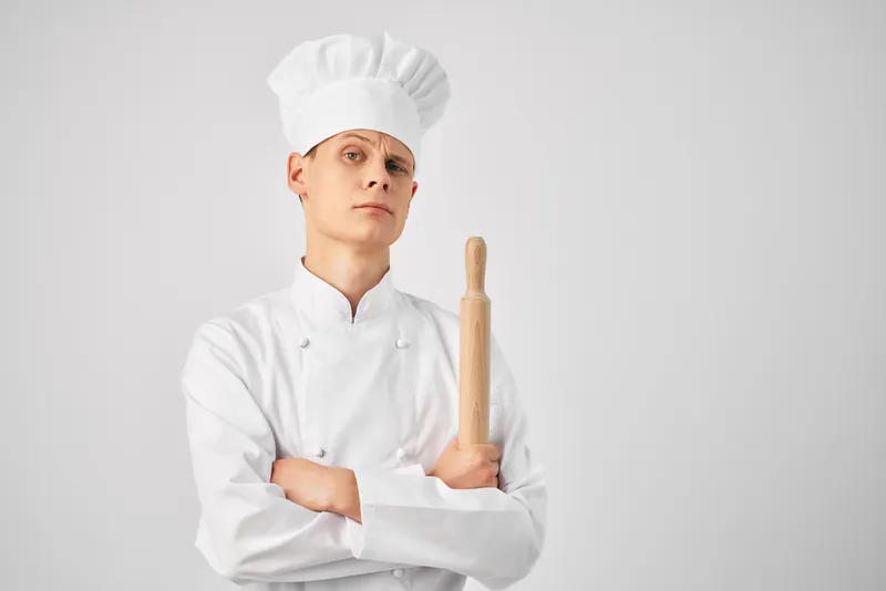 Мужчина в поварской форме на кухне, его профессия — работа на светлом фоне