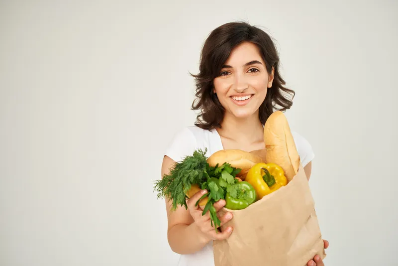 Брюнетка с пакетом продуктов, овощи, здоровая пища, студия