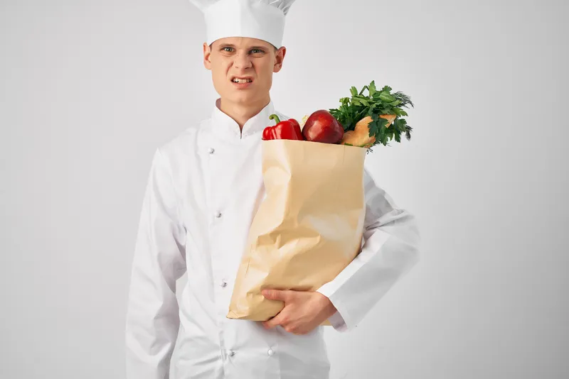 Мужчина с упаковкой еды на кухне ресторана