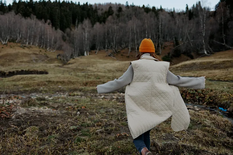 Турист в оранжевой шапке отдыхает на берегу реки осенью