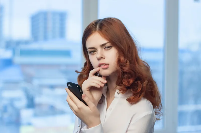 Симпатичная женщина в рубашке с телефоном в руке, технологии, профессионал, официальный стиль
