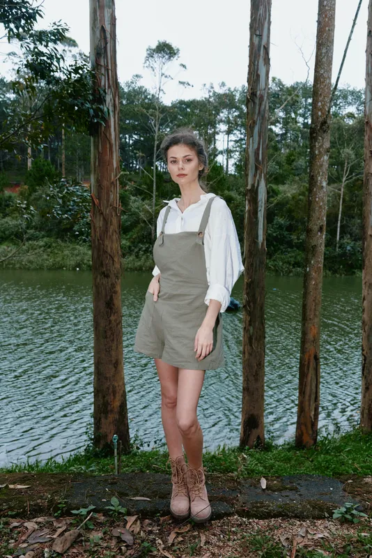 Young woman in casual outfit by the lake, showcasing a relaxed style with a mix of earth tones and nature backdrop, perfect for lifestyle and outdoor themes