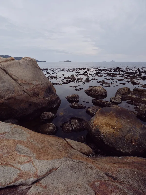 Scenic rocky shoreline with calm water, showcasing natural beauty during an overcast day, ideal for nature enthusiasts and travel themes