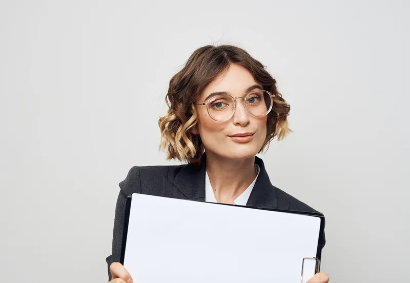 Женщина в деловом костюме с белым листом бумаги на работе, очки, макет