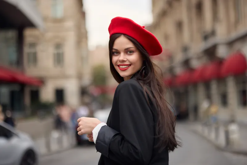 Модная женщина улыбается, обнажая зубы, стоя на улице на фоне города