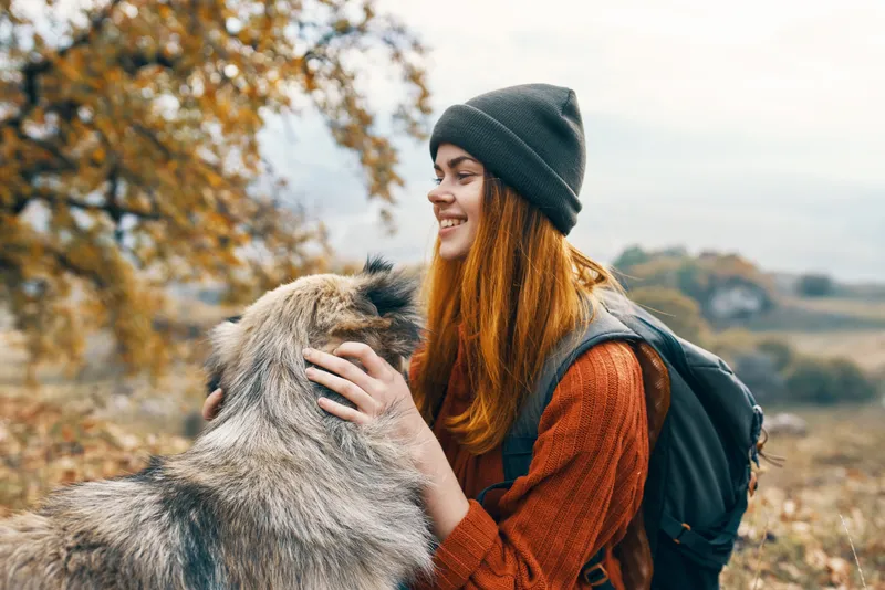 Веселая женщина-туристка играет с собакой на природе, пейзаж, дружба