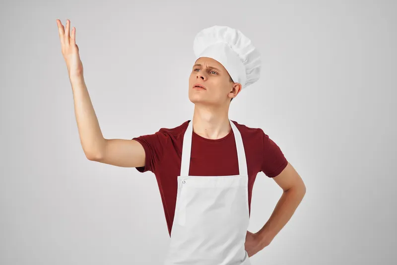 Мужчина в белом фартуке работает на кухне шеф-поваром, отражена атмосфера повседневной жизни