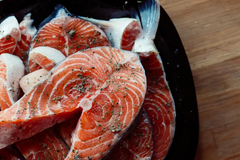Маринованная красная рыба на тарелке, приготовление морепродуктов, деликатес