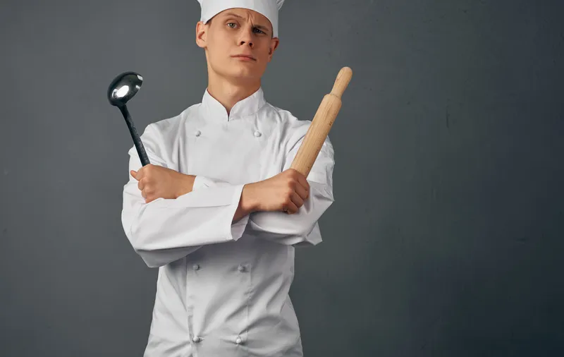 Шеф-повар-мужчина с кухонной утварью, готовящий в ресторанной студии