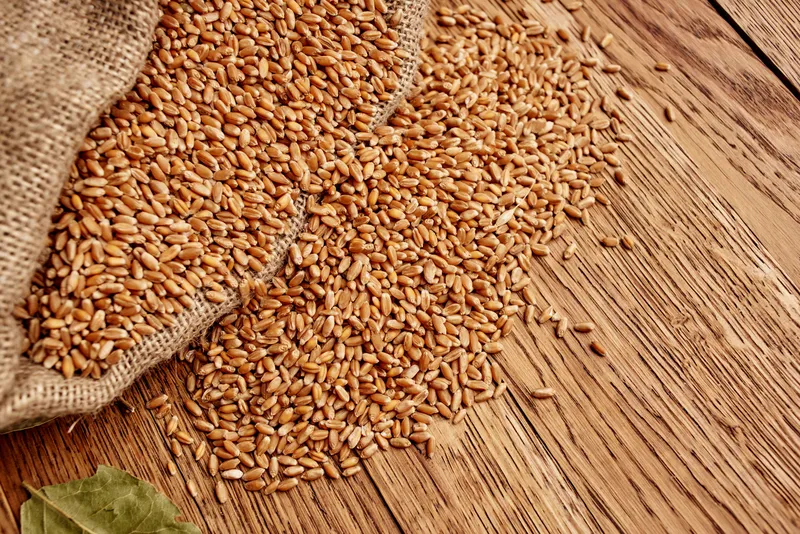На столе на деревянном фоне лежат хлопья для завтрака и кухонные продукты
