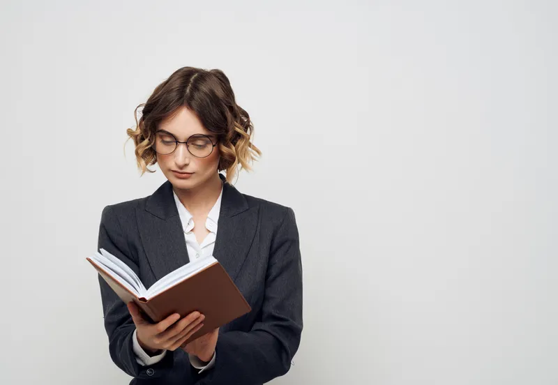 Деловая женщина держит в руках книгу на светлом фоне