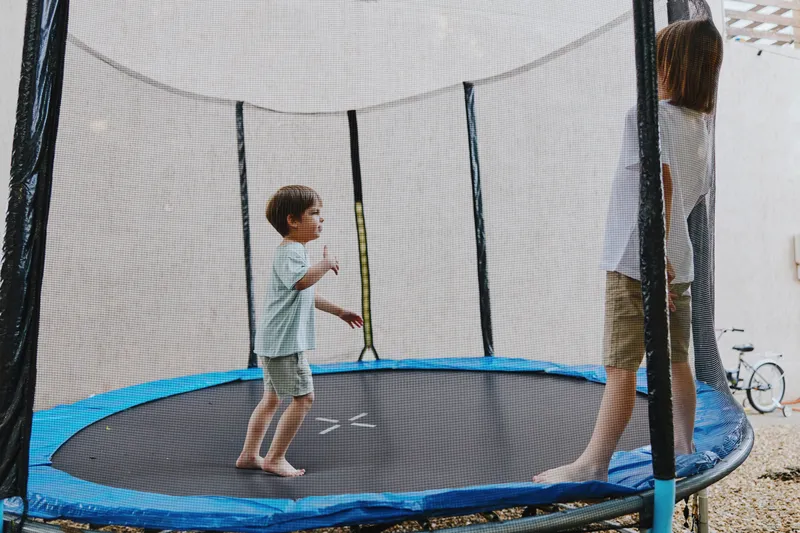 Active children playing joyfully on a trampoline, showcasing fun and excitement. The vibrant atmosphere captures the essence of childhood playtime.