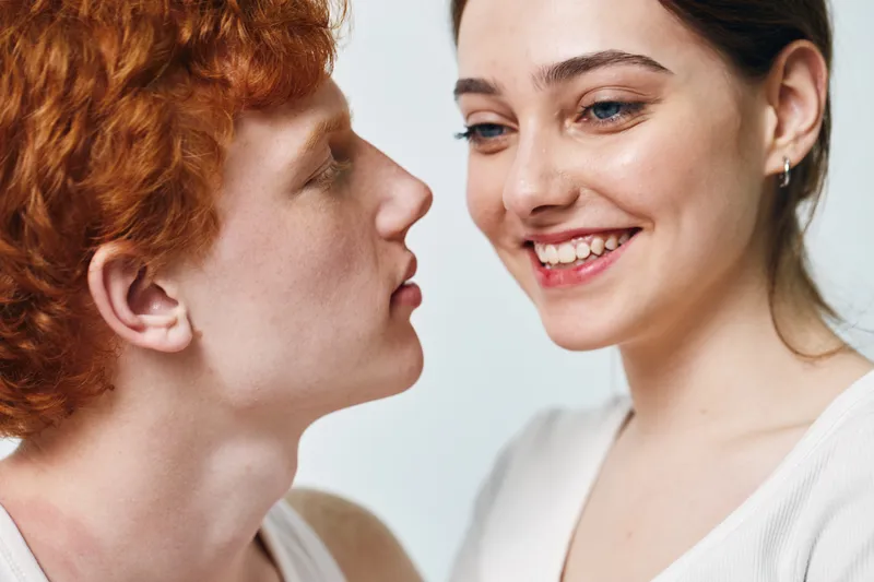 Couple with red hair and brown hair smiling together in closeup portrait, young people with joy and happiness, intimate moment showing affection and connection between two friends.