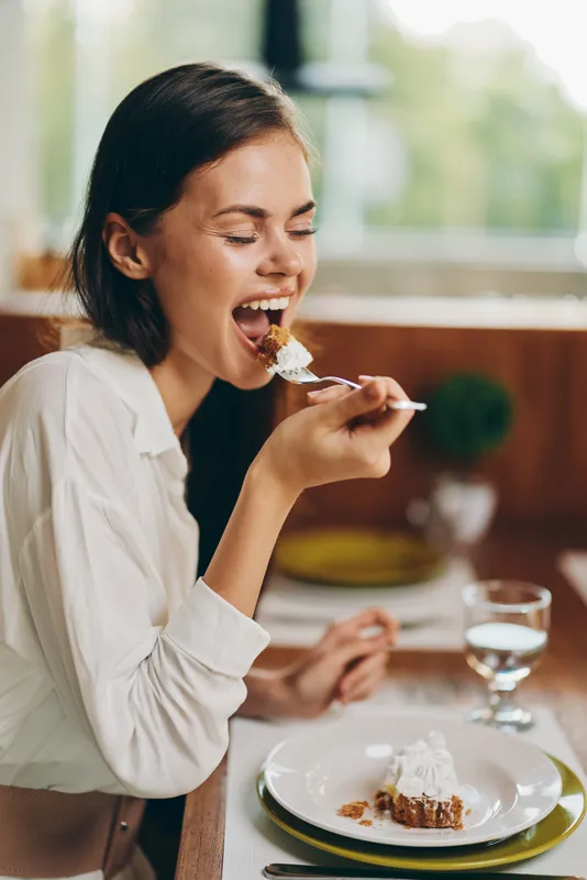 Счастливая женщина наслаждается романтическим ужином дома с вкусным домашним тортом и вином