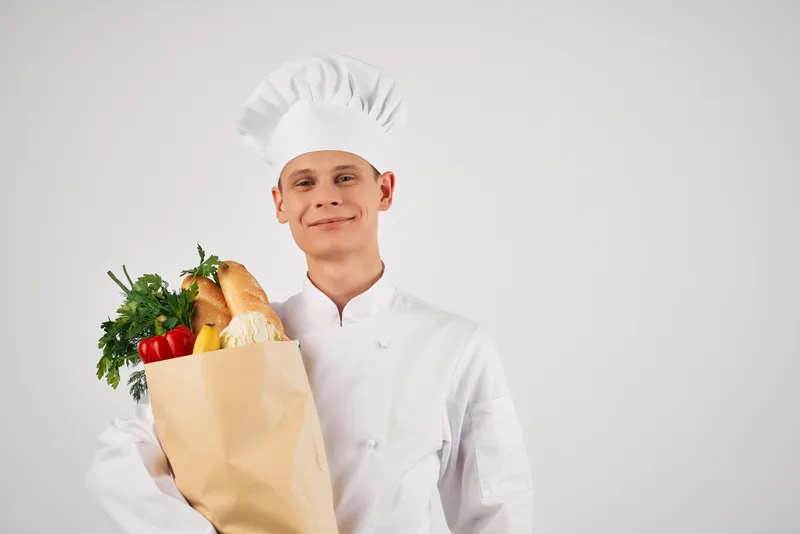 Мужчина в одежде шеф-повара с пакетом продуктов, здоровая еда, обслуживание на кухне