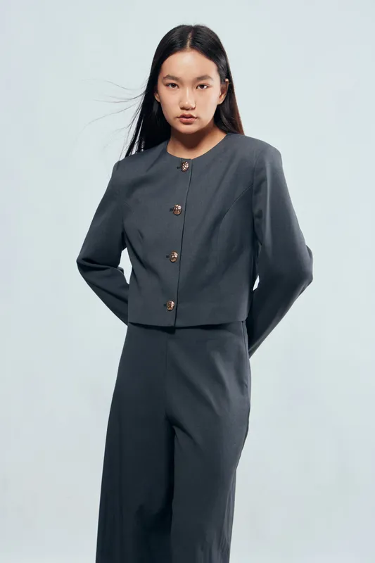 Young Asian woman wearing grey modern tailored suit with buttons posing standing confident isolated on light background. Fashion style, business casual and professional look for office or formal