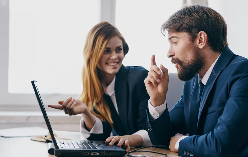 Мужчина и женщина в деловых костюмах работают за ноутбуком, финансовый менеджер