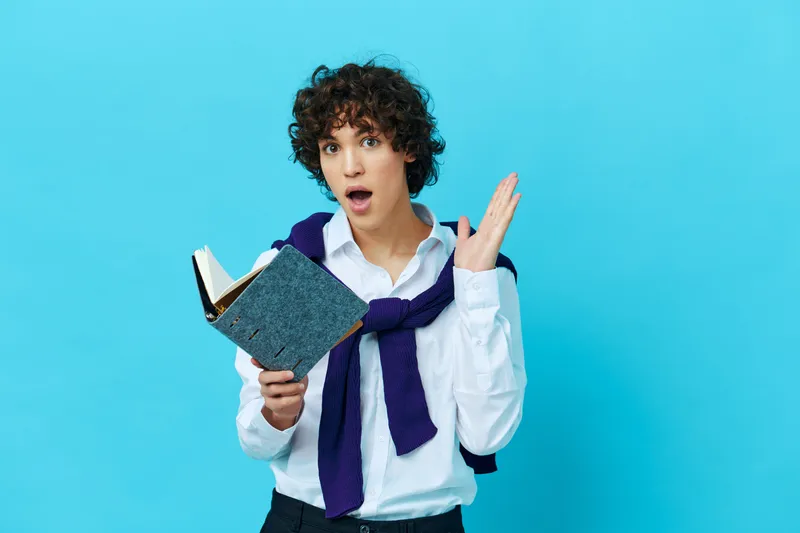 Молодой человек с книгой в колледже, одетый в куртку, на изолированном фоне