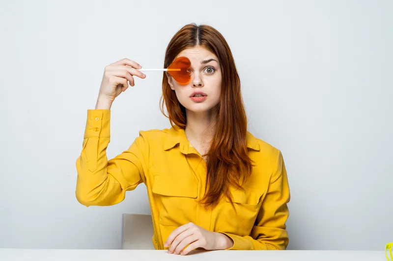 Портрет женщины в желтой рубашке, сидящей за столом у стены, крупным планом у лица