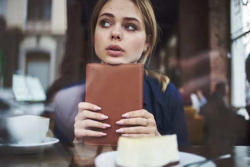 Деловая женщина с книгой в руках и чашкой кофе в кафе, ведущая активный образ жизни
