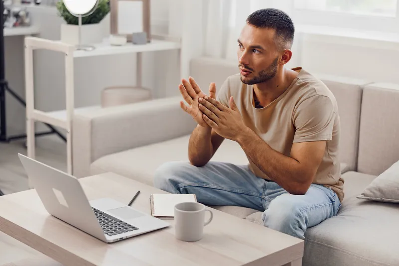 Engaged man discussing ideas during a video call, surrounded by a modern, bright living space, evoking inspiration and productivity.