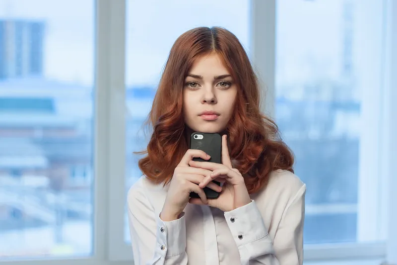 Женщина в рубашке с телефоном в руках, офис, технологии