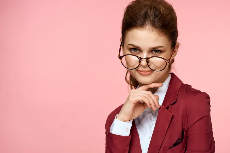 Бизнесвумен в красном пиджаке и очках, образ руководителя, образ жизни в студии на розовом фоне