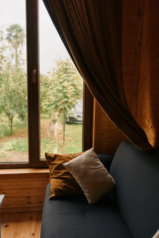 Curtain and pillow on sofa in cozy wooden interior