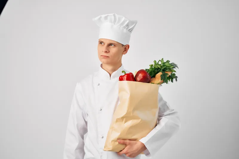 Мужчина в униформе повара с упаковкой продуктов для работы в ресторанной службе доставки