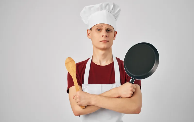 Мужчина-повар в фартуке на кухне ресторана, ведущий образ жизни