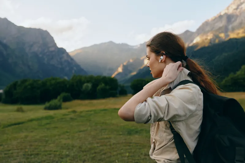 Young woman with backpack explores a expansive mountain valley, enjoying fresh air, tranquil scenery, and a calm, reflective mood