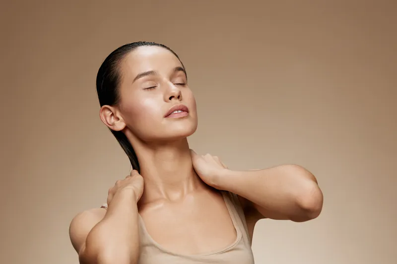Young woman with closed eyes enjoying skincare treatment, showcasing natural beauty and wellness in neutral tones, emphasizing self care and relaxation