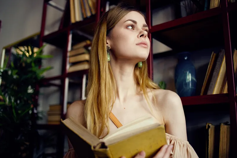 Женщина читает книгу в ресторане во время отпуска, занимаясь самообразованием