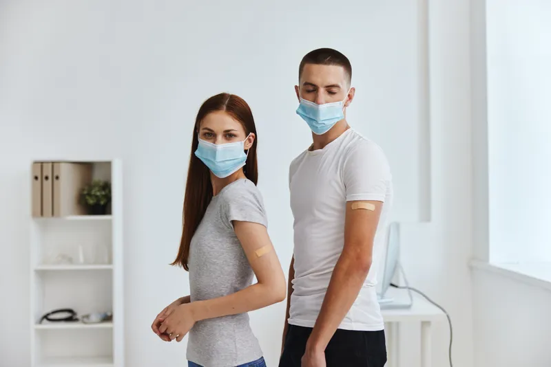 Мужчина и женщина в медицинских масках, паспорт вакцинации от COVID-19
